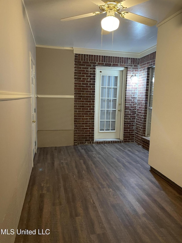 empty room featuring ceiling fan, ornamental molding, and brick wall