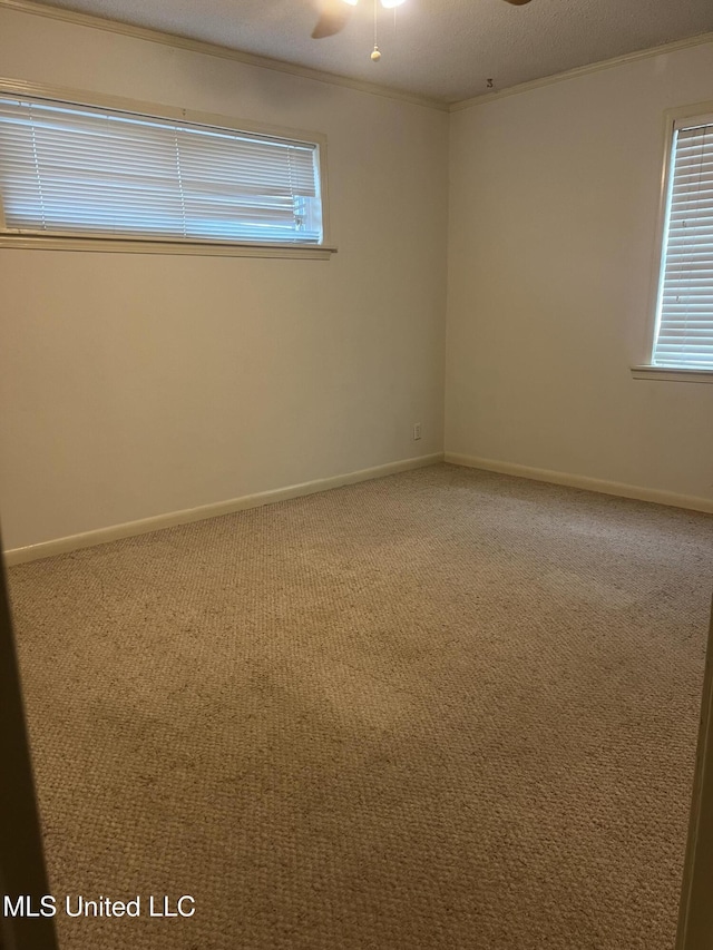 empty room featuring crown molding, carpet floors, a ceiling fan, and a healthy amount of sunlight