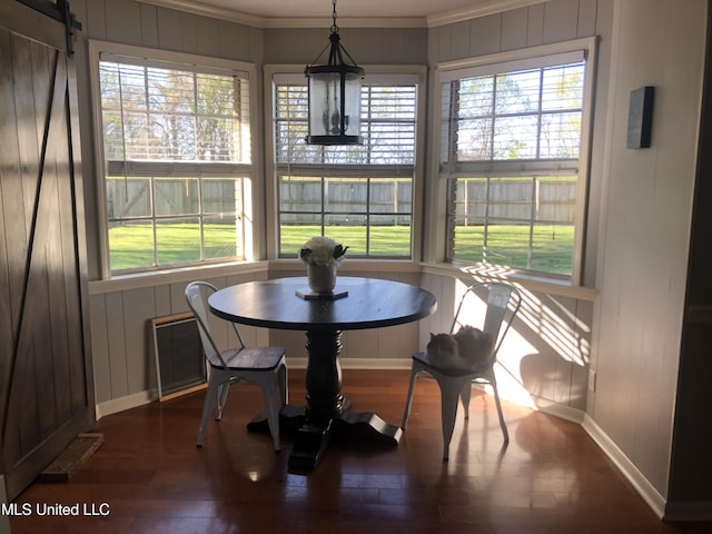 dining space featuring a barn door, wood finished floors, a wealth of natural light, and baseboards