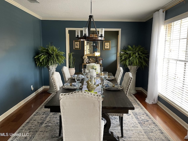 dining area with baseboards, a textured ceiling, wood finished floors, and crown molding