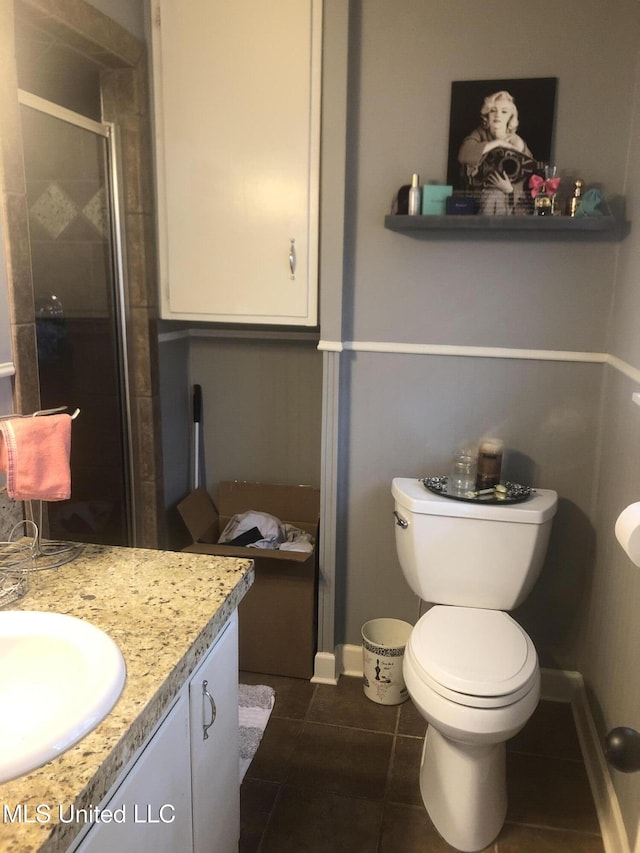 full bath featuring toilet, a stall shower, vanity, baseboards, and tile patterned floors