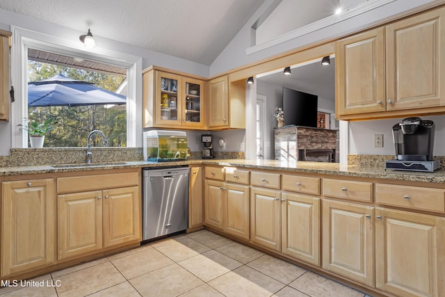 kitchen featuring light stone countertops, stainless steel dishwasher, vaulted ceiling, sink, and light tile patterned flooring