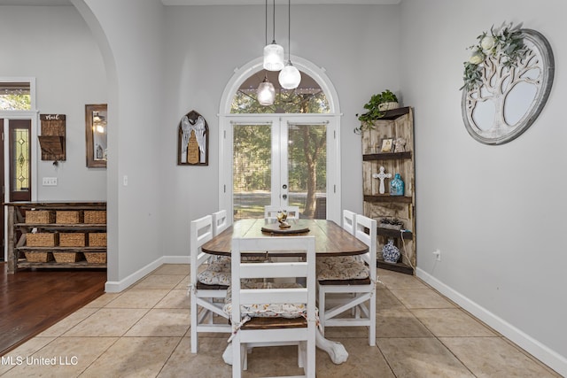 tiled dining room with french doors and a towering ceiling