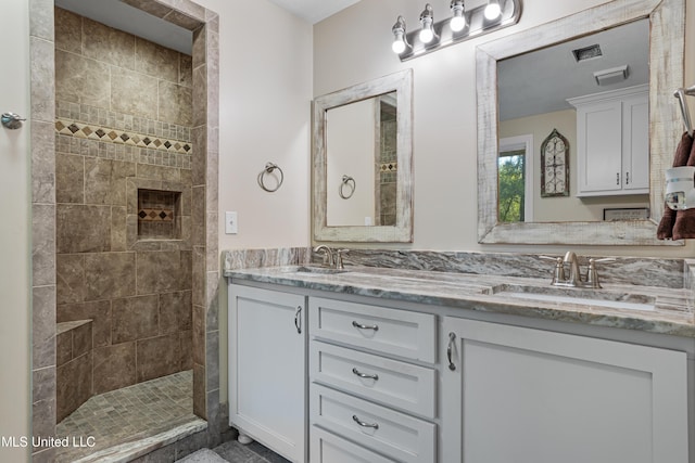 bathroom with a tile shower and vanity