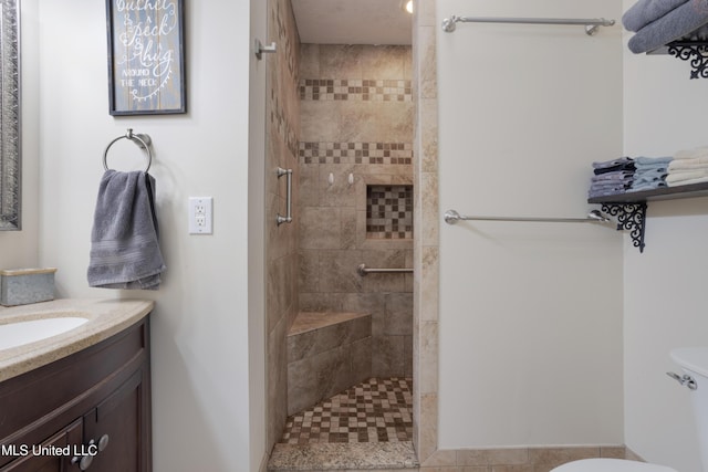 bathroom featuring vanity, toilet, and tiled shower