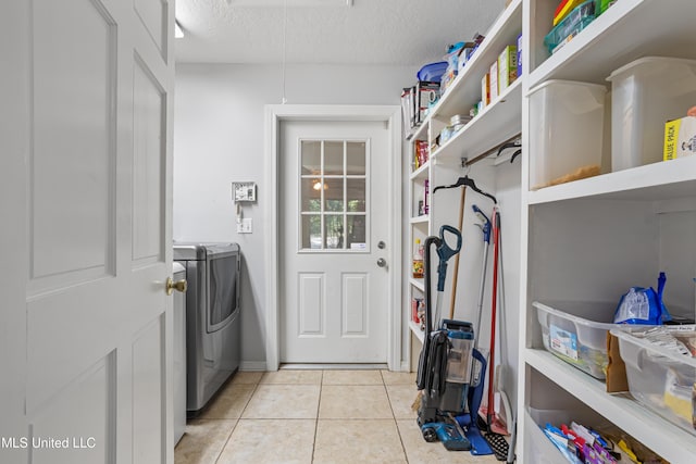 laundry area with light tile patterned floors, a textured ceiling, and washer / clothes dryer