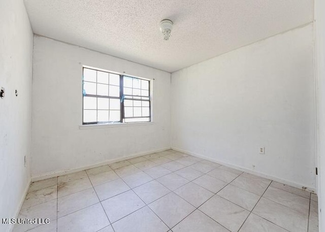 tiled spare room featuring a textured ceiling