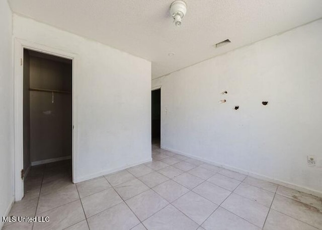 empty room featuring light tile patterned floors and a textured ceiling