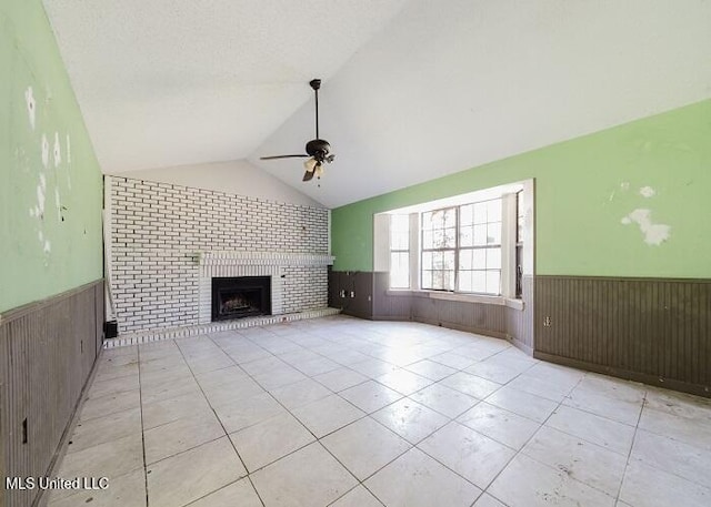 unfurnished living room featuring ceiling fan, light tile patterned floors, a fireplace, lofted ceiling, and wood walls