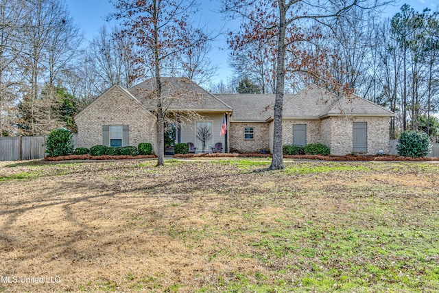 ranch-style house with a front yard, fence, and brick siding