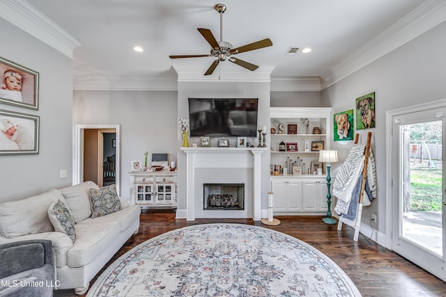 living room featuring visible vents, ceiling fan, ornamental molding, dark wood-type flooring, and a fireplace