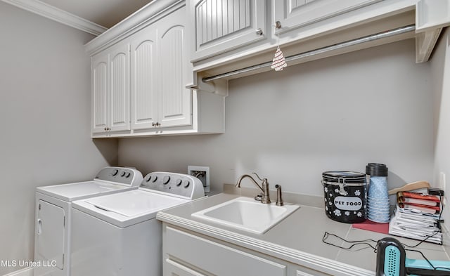 clothes washing area featuring cabinet space, washing machine and dryer, crown molding, and a sink