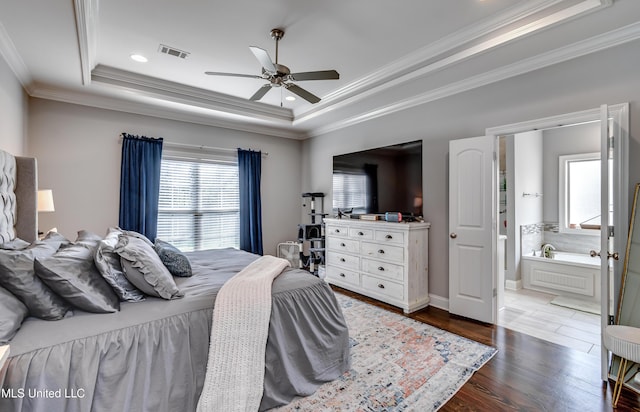 bedroom featuring visible vents, connected bathroom, ornamental molding, dark wood-type flooring, and a tray ceiling