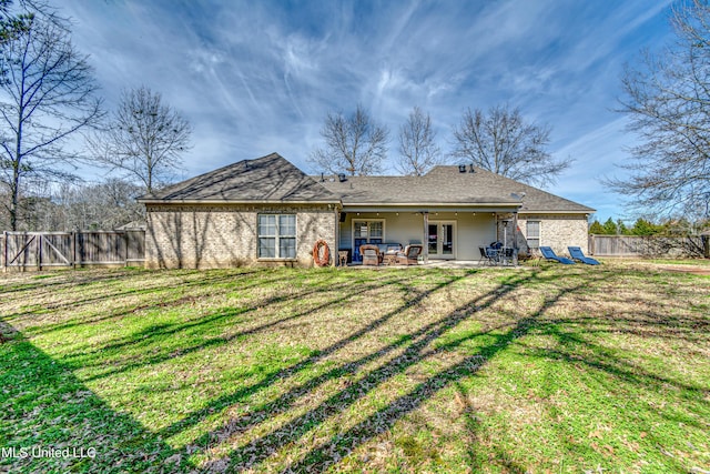 back of property with ceiling fan, a patio, a fenced backyard, french doors, and a lawn