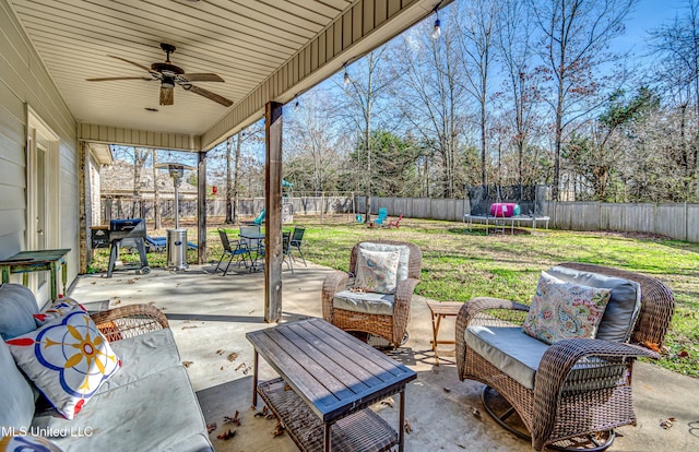 view of patio with ceiling fan, a trampoline, a fenced backyard, and an outdoor living space