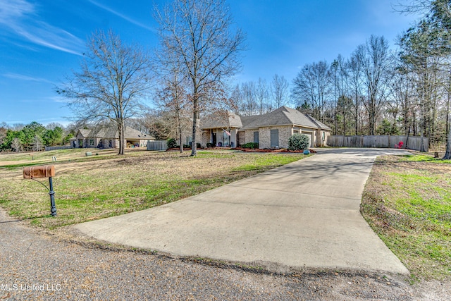 single story home with driveway, stone siding, an attached garage, fence, and a front yard