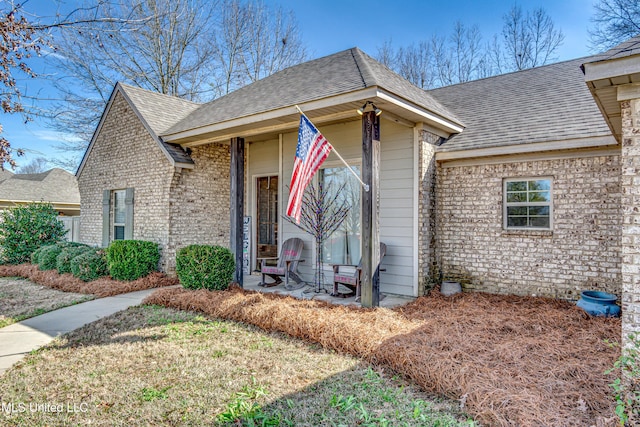 view of front of home featuring a shingled roof and brick siding