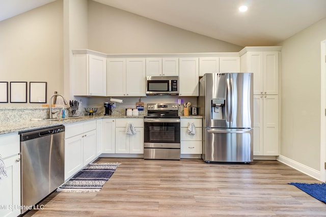 kitchen with appliances with stainless steel finishes, white cabinets, a sink, and light wood-style flooring