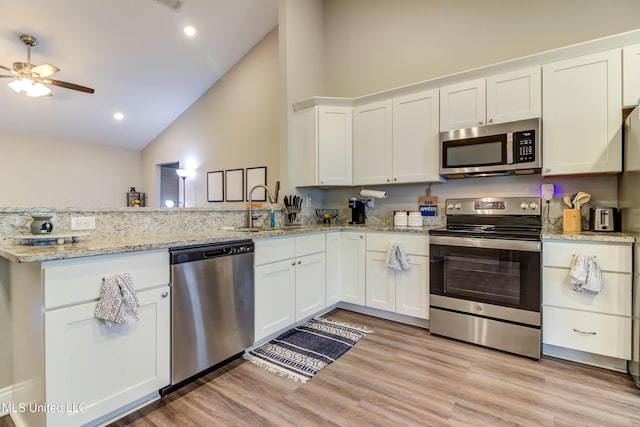 kitchen with stainless steel appliances, light wood-style flooring, white cabinets, a sink, and a peninsula