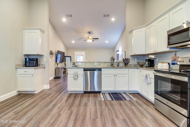 kitchen with visible vents, appliances with stainless steel finishes, a peninsula, white cabinetry, and a sink