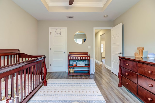 bedroom featuring visible vents, a raised ceiling, and wood finished floors