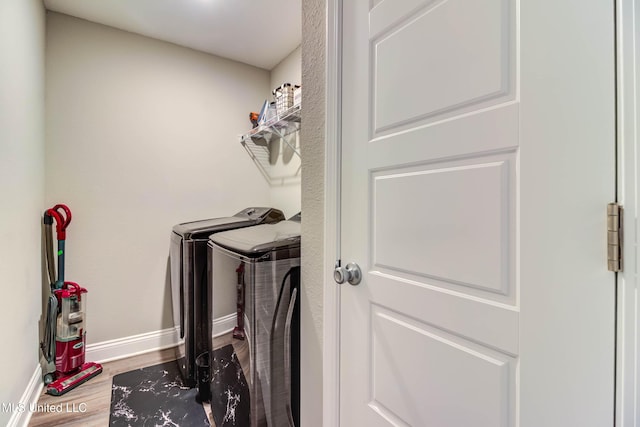 laundry room featuring laundry area, baseboards, wood finished floors, and washing machine and clothes dryer