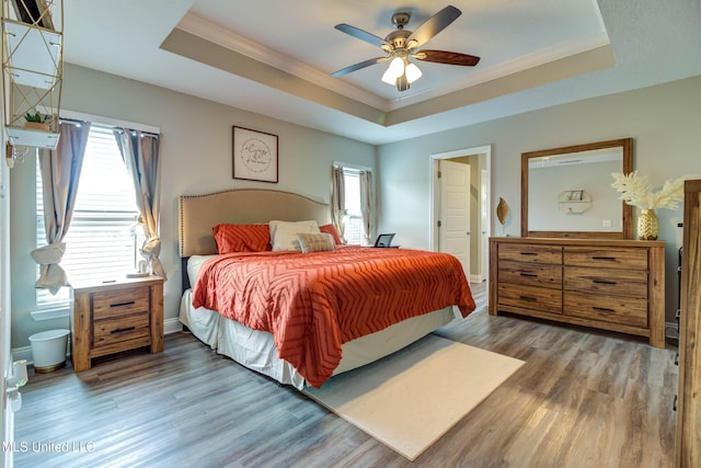 bedroom featuring ornamental molding, a tray ceiling, and wood finished floors