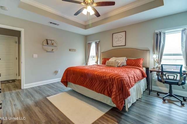 bedroom featuring ornamental molding, a tray ceiling, and wood finished floors