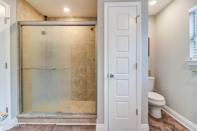 bathroom with toilet, a shower stall, baseboards, and recessed lighting