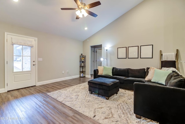 living room with a ceiling fan, high vaulted ceiling, baseboards, and wood finished floors