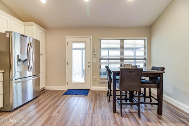 dining area with lofted ceiling, light wood-style flooring, and baseboards