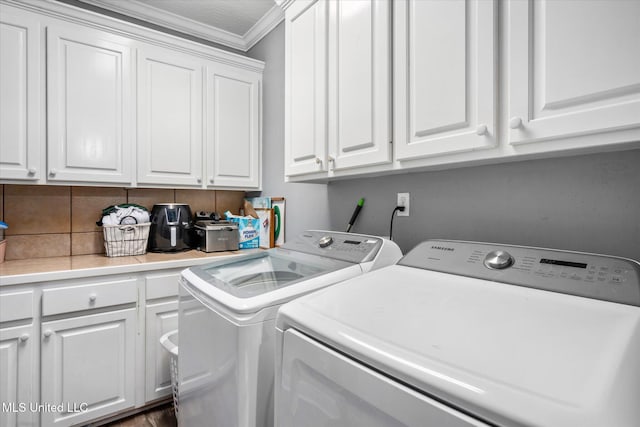 laundry area with washer and clothes dryer, cabinets, and ornamental molding