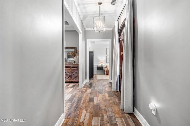 hall with dark hardwood / wood-style flooring, a notable chandelier, and ornamental molding