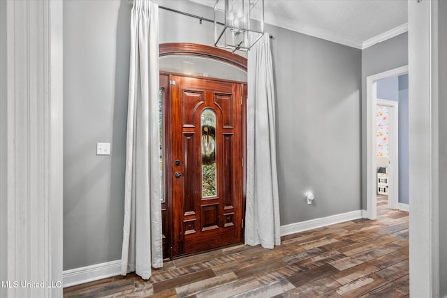 entrance foyer with dark hardwood / wood-style flooring, crown molding, and an inviting chandelier