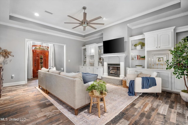 living room featuring a tray ceiling, crown molding, ceiling fan, and dark hardwood / wood-style floors