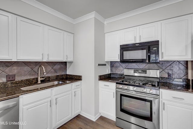 kitchen with crown molding, dark stone countertops, wood finished floors, stainless steel appliances, and a sink