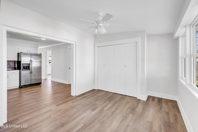 interior space featuring a closet, baseboards, stainless steel fridge with ice dispenser, and light wood finished floors