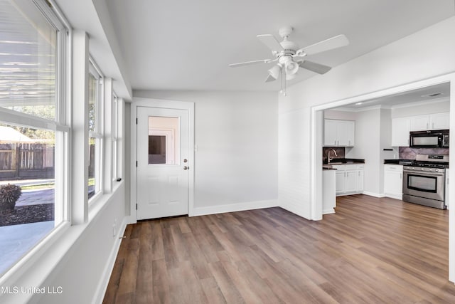 interior space with a sink, baseboards, dark wood-style floors, and ceiling fan