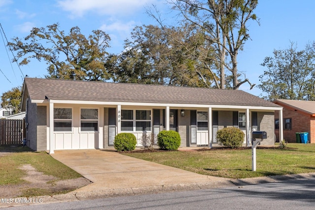 ranch-style home featuring a porch, brick siding, a shingled roof, a front lawn, and board and batten siding