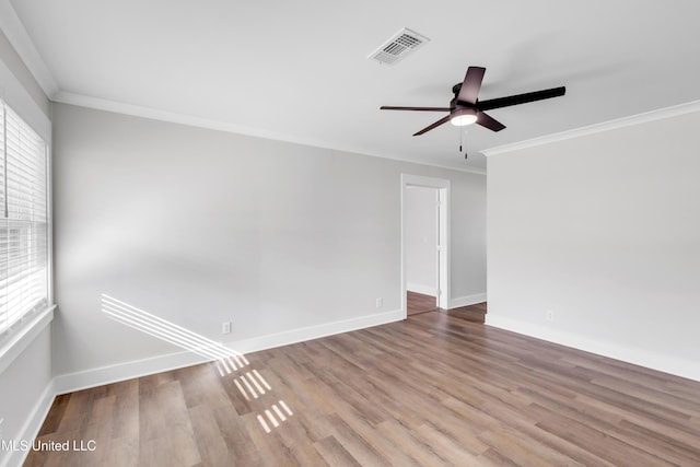 empty room featuring baseboards, wood finished floors, visible vents, and ornamental molding