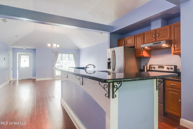 6909 N Rue Mornay, Biloxi, MS 39532 - kitchen with under cabinet range hood, appliances with stainless steel finishes, a kitchen breakfast bar, brown cabinetry, and wood finished floors