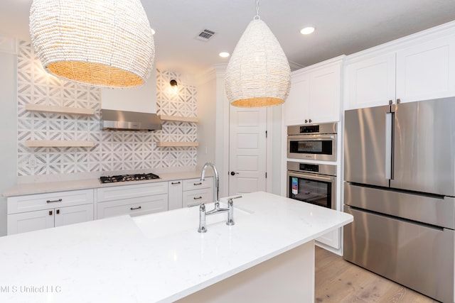 kitchen with light stone counters, appliances with stainless steel finishes, light hardwood / wood-style floors, and white cabinets