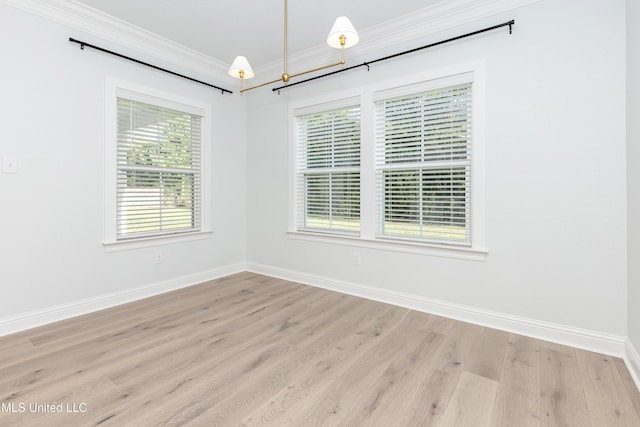 spare room featuring crown molding, a healthy amount of sunlight, and light wood-type flooring