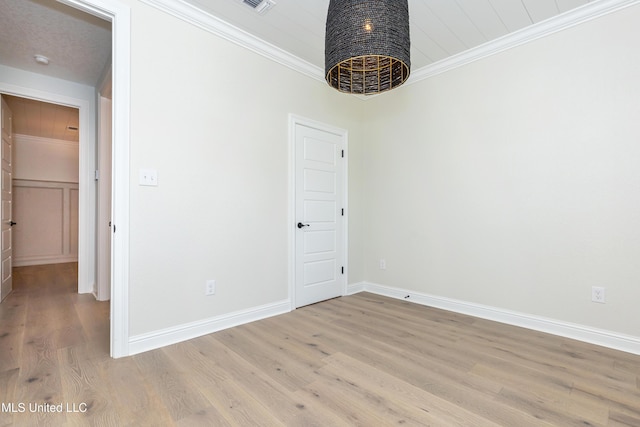 unfurnished room with ornamental molding and light wood-type flooring