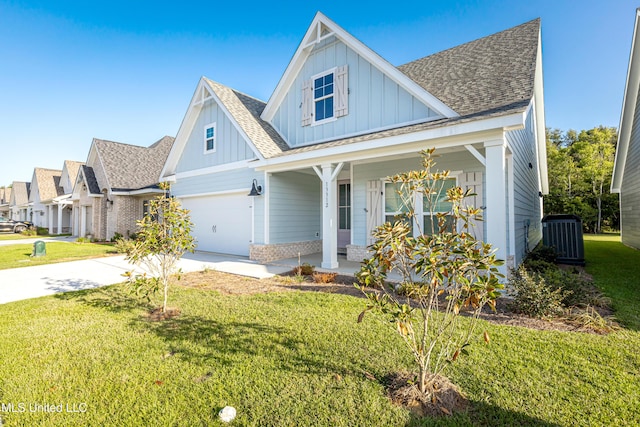 view of front of house with a garage, a front yard, central AC unit, and covered porch