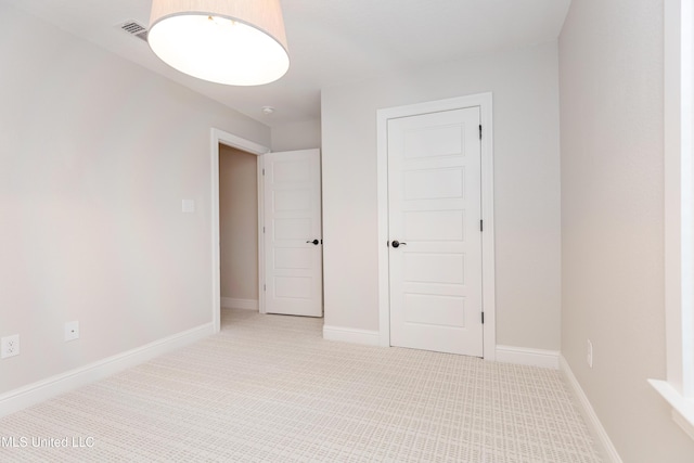 unfurnished bedroom with light colored carpet and a closet