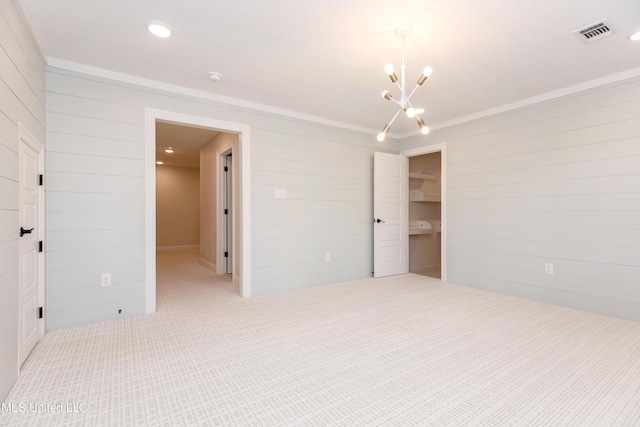 unfurnished bedroom featuring a spacious closet, a closet, a chandelier, and wood walls