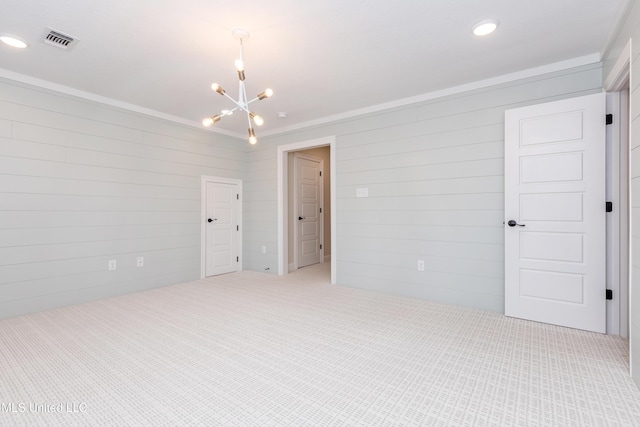 empty room featuring carpet floors, wooden walls, and a chandelier