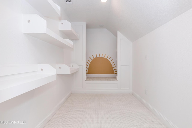 bathroom featuring lofted ceiling, tile patterned flooring, and a textured ceiling