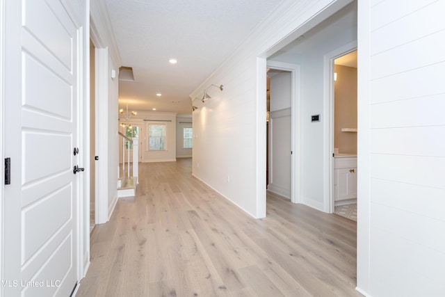 corridor featuring crown molding and light hardwood / wood-style flooring